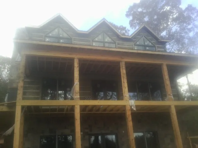 Dormers and porch framing on a large log home under construction — Roof Coating work by our crew in Trafford