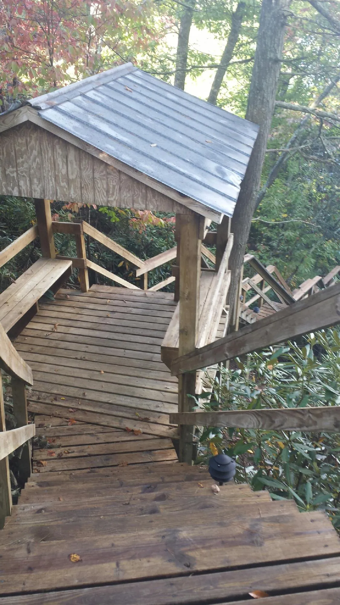 Metal roofed shelter over wooden steps on a wooded walkway — Skylight Repair & Installation work by our crew in Trafford